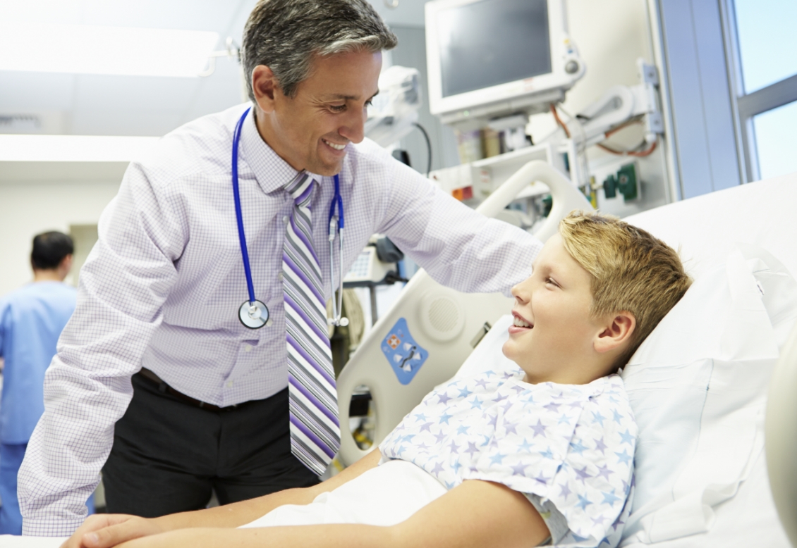 Doctor speaking to child patient at bedside.